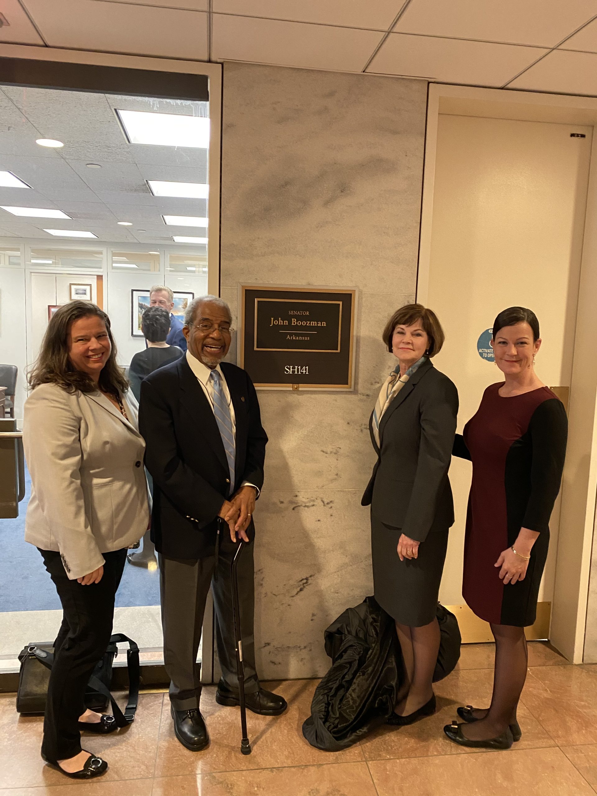 Erin Prangley from NACDD, Robert Richardson, Loretta Herrington from WID and Danielle Applegate from VetsFirst stand together around plaque outside Senator Boozman's office